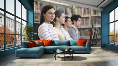 Portrait of teenage girl with friends in row using laptops in library Wall mural