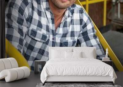 Portrait of young male worker with wrench sitting on steps at industry Wall mural