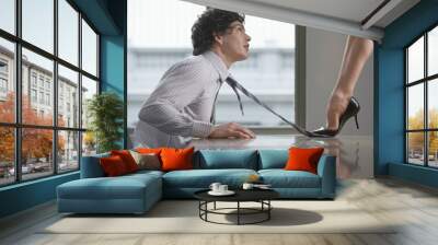 side view of a highheeld businesswoman stepping on businessman's tie on desk Wall mural