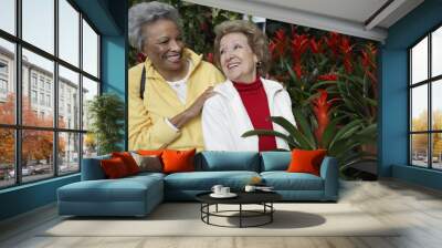 Two happy multiethnic senior female friends at botanical garden Wall mural