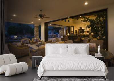 Wicker furniture in lit spacious home with porch view at night Wall mural