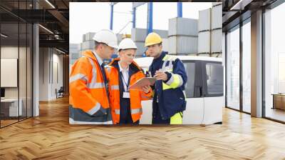 Workers discussing over clipboard beside car in shipping yard Wall mural