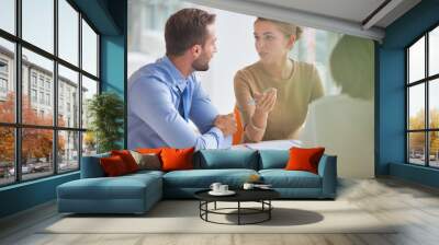 Young colleagues discussing over document at table during meeting in new Wall mural