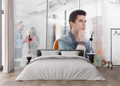 Young thoughtful businessman working in office Wall mural