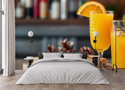 A glass of orange juice with a slice of orange and waffles in Christmas decorations, Two glasses of orange juice with ice on a wooden table in a restaurant, Glasses of tasty orange cocktail on table. Wall mural