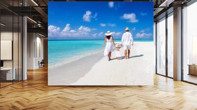 A beautiful family walks together on a tropical paradise beach in the Maldives with turquoise ocean and white sand during their vacation time Wall mural