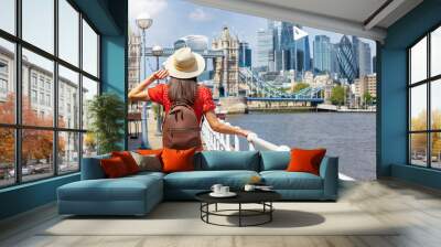 A beautiful tourist woman in a red dress enjoys the summer day view of the London skyline with Tower Bridge and City, England Wall mural