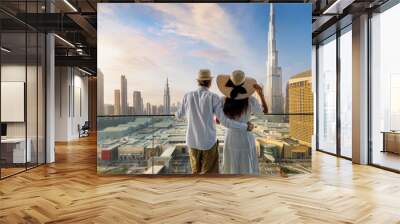 A elegant tourist couple on vacation time stands on a balcony and enjoys the sunrise view of the Dubai city skyline, UAE Wall mural