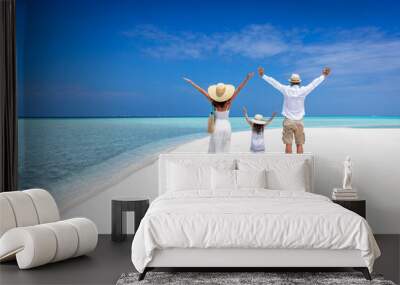 A happy family stands together on a tropical paradise beach with turquoise ocean and white sand during their vacation time Wall mural