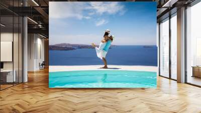 A happy summer holiday couple stands hugging a the swimming pool with view to the mediterranean sea Wall mural