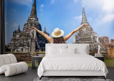 A happy tourist woman on a sightseeing trip stands in front of the buddhistic temple ruins at the historic city of Ayutthaya, Thailand Wall mural