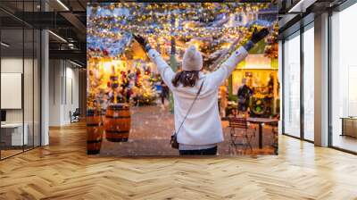 A happy tourist woman stands on a christmas market in Copenhagen, Denmark, with snow and illuminated decorations during winter time Wall mural