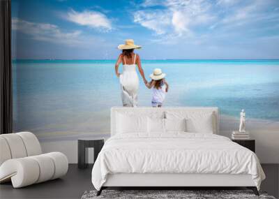 A mother and daughter in white dresses running into the turquoise sea of the Indian Ocean, Maldives, during their beach holidays Wall mural