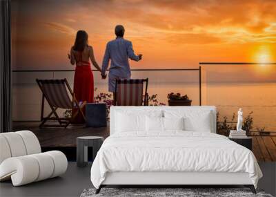 A romantic couple on summer vacation enjos the sunset over the mediterranean sea by the pool with a glass of wine Wall mural