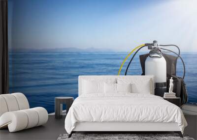 A scuba diving tank and gear standing on a boat bow with blue sea and sunshine as a banner with copy space Wall mural