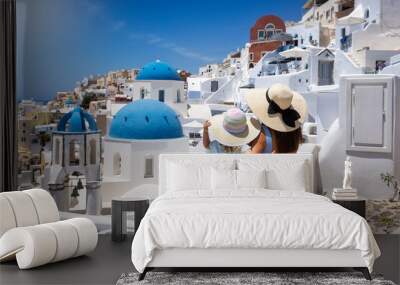 A tourist mother and her daughter looking at the whitewashed houses of the village Oia, Santorini island, Greece, during summer holiday time Wall mural