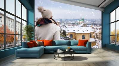 A tourist woman enjoys the panoramic view of the snow covered skyline of Prague, Czech Republic, during a cold winter day Wall mural