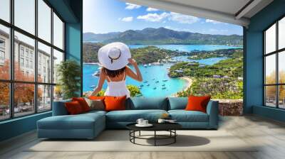 A tourist woman in a white dress enjoys the panoramic view over the landscape of Antigua island with English Harbour and Shirley heights Wall mural