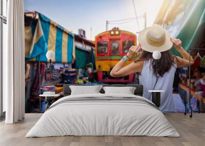 A tourist woman on sightseeing tour visits the famous train and railway market in Maeklong, Thailand, during early morning hours Wall mural