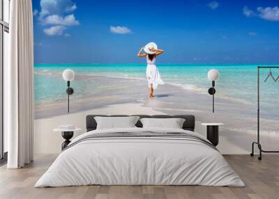 A woman in a white summer dress stands on a sandbar surrounded by turquoise ocean in the Maldives islands Wall mural