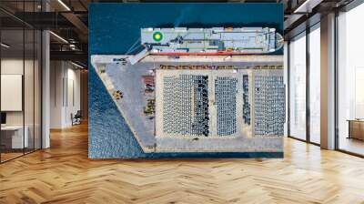 Aerial top down view of an industrial car port terminal with a cargo ship unloading and rows of new vehicles for delivery Wall mural