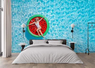 Aerial view of a beautiful woman in bikini on a watermelon shaped float  in a swimming pool with copy space Wall mural