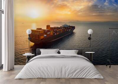 Aerial view of a large, heavy loaded container cargo ship sailing over calm sea into the sunset Wall mural