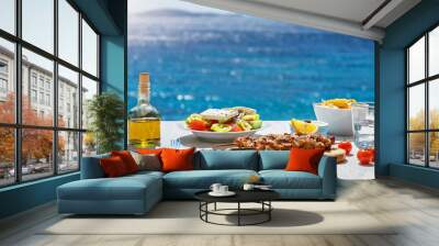 Greek food concept with farmers salad and souvlaki skewers in front of the sparkling, blue Aegean sea during summer time Wall mural