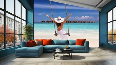 Tropical vacation concept: happy female traveller in a white dress on a swing enjoys her summer holiday Wall mural