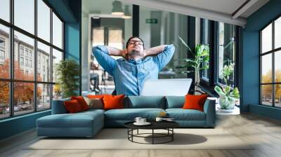 Businessman relaxing with closed eyes while working on laptop at home office Wall mural