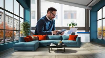 Businessman using digital tablet while working on laptop at office desk Wall mural