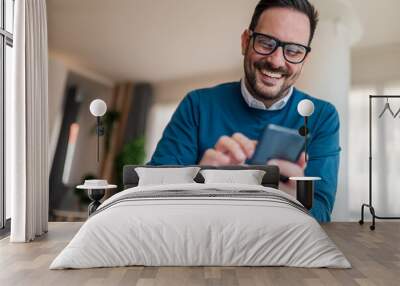 Close-up of smiling male entrepreneur networking on smart phone at office Wall mural