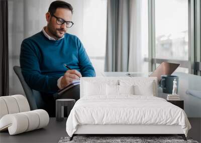 Confident entrepreneur making business plan in diary while working at office Wall mural