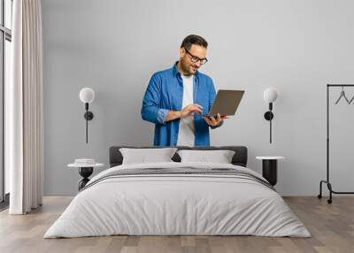 Confident male entrepreneur analyzing report over laptop while standing over white background Wall mural