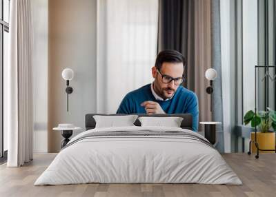 Confident professional making plan while working on laptop at desk in office Wall mural