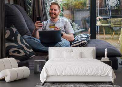 Excited caucasian man making a self portrait, holding a credit card. Wall mural