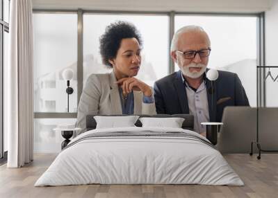 Focused partners analyzing business plan on laptop during office meeting Wall mural