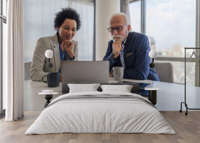 Focused partners analyzing business plan on laptop during office meeting Wall mural