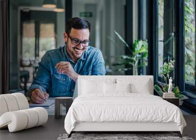 Happy entrepreneur making business plan while working on laptop at home office Wall mural