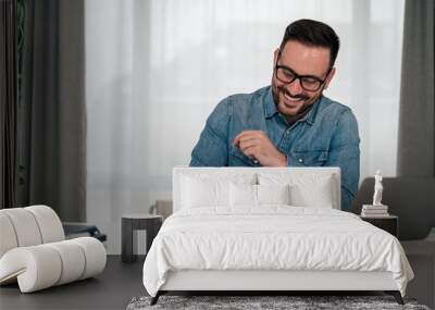 Laughing young adult manager, organizing his busy schedule. Wall mural