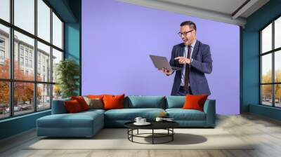 Male entrepreneur screaming cheerfully while attending online meeting isolated on blue background.Young businessman shouting ecstatically and celebrating project success while using wireless computer Wall mural