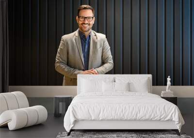 Portrait of confident male receptionist in eyeglasses looking at camera and standing at lobby desk Wall mural