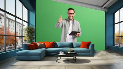 Portrait of happy handsome customer using touchpad and showing thumbs up sign on green background Wall mural