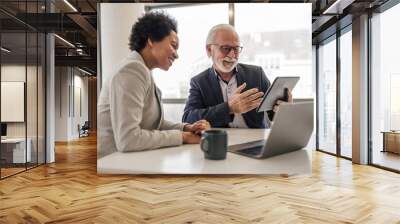 Senior businessman explaining strategy to female coworker Wall mural