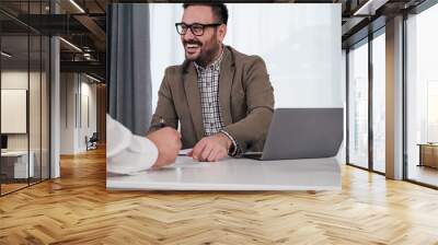 Smiling entrepreneur discussing with business partner in meeting at the office desk. Wall mural