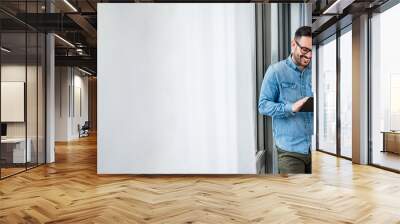 Smiling man businessman in casuals standing in office next to window using tablet making online shopping purchasing Small business home office entrepreneur looking at tablet making online video call Wall mural