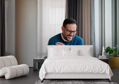 Smiling young manager looking at successful business plan on laptop Wall mural