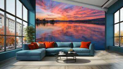 A beautiful sunset over a lake with a reflection of the sky on the water. The sky is a mix of pink and orange hues, creating a serene and peaceful atmosphere Wall mural