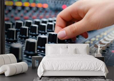 Close-up of a hand adjusting knobs on a professional audio mixing console, controlling sound levels and settings in a studio. Wall mural