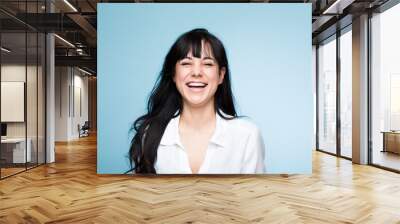 Smile, laughing and portrait of a beautiful woman isolated on a blue background in a studio. Happy, young and a headshot of a girl in a shirt with confidence, empowerment and looking stylish Wall mural